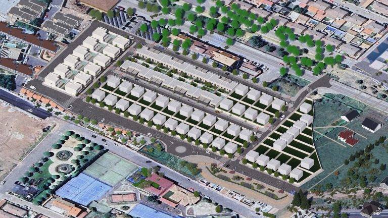 Vista aérea de un proyecto urbanístico que incluye varias edificaciones y áreas verdes, rodeado de calles y otras construcciones. Se observa una disposición organizada de las viviendas y espacios recreativos.